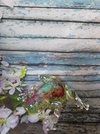 Grenouille transparente à paillettes avec des fleurs.